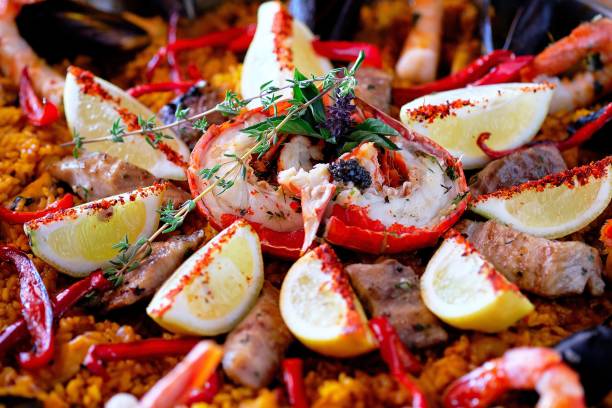 plan rapproché du délicieux plat de paella aux fruits de mer espagnol - seafood lobster paella prepared shellfish photos et images de collection