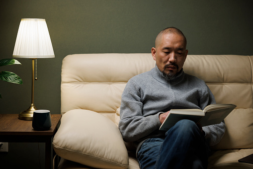 Asian middle-aged man sitting on the sofa reading