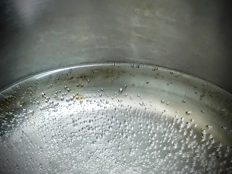 Close Up of Hot Water Boiling and Creating Bubbles in A Pot.