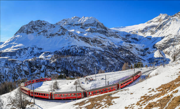 o trem vermelho da rhaetian railway está passando pelos trilhos do trem com uma curva apertada de 180° - rhätische bahn - fotografias e filmes do acervo