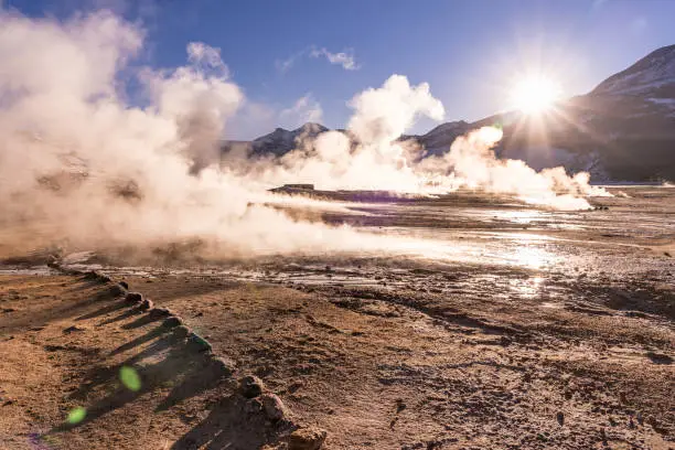 Sunrise at Geyser El Tatio near San Pedro de Atacama in Chile. Landscape with gas smoking and people in backlight.