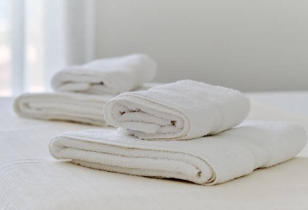istock Folded white towels lying on bed in bedroom 1454766318