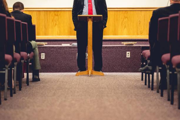 istock Male wearing a black suit and giving a speech next to a pulpit 1454766414
