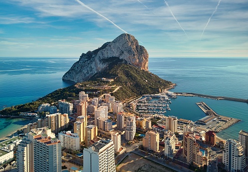 Drone view of Penon de Ifach rock, harbor, Mediterranean sea rooftops of houses Calpe cityscape. Coastal town located in comarca of Marina Alta ,Spain