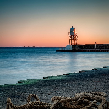 A rope at the coast on the background of a lighthouse during sunset near Helsingborg, Sweden