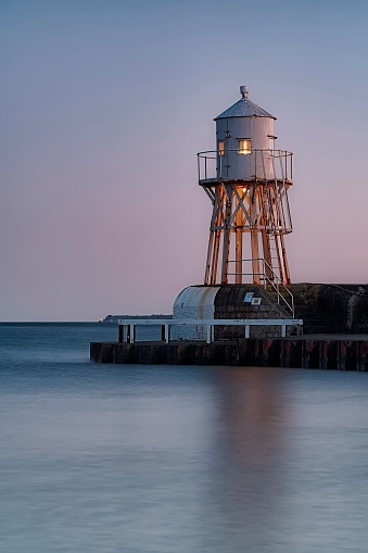 A vertical shot of a lighthouse at the Swedish village Raa on the outskirts of Helsingborg at sunset