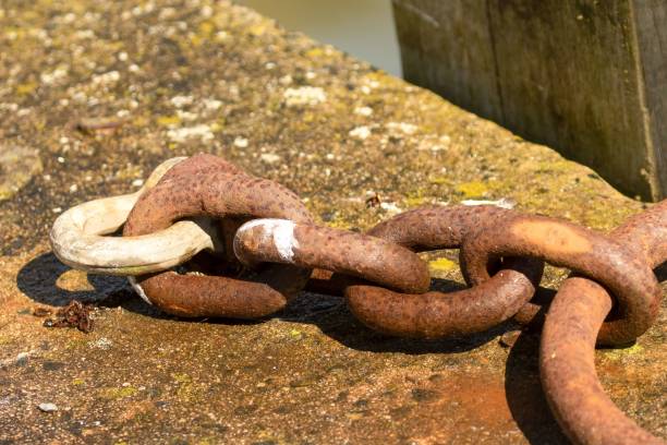 closeup shot of a rusty weatherd chain on harbor quay side - weatherd imagens e fotografias de stock