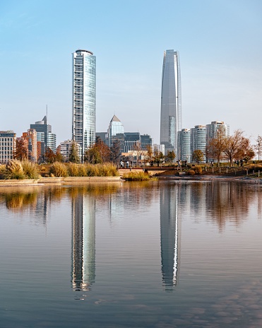 santiago, Chile – October 23, 2022: A vertical of Costanera center's tallest buildings reflecting in a lake in Vitacura, Santiago, Chile