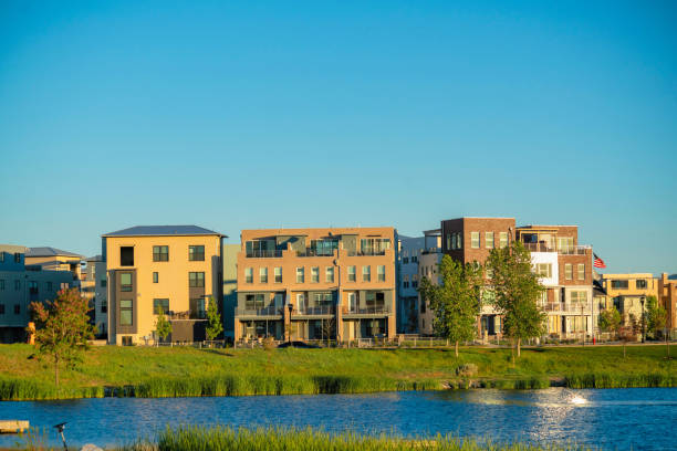 istock Tree buildings with grassland and a like against them under the clean sky 1454779737