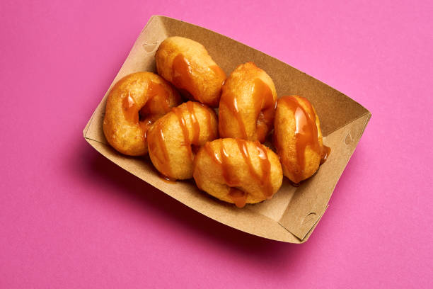 istock Top view on fresh donuts with drizzled caramel on a pink background. 1454779783