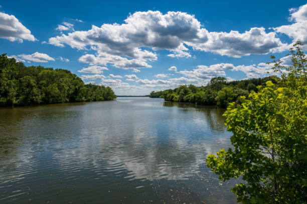 istock Beautiful inlet with trees around the water under a bright cloudy sky reflecting on the clear water 1454780081