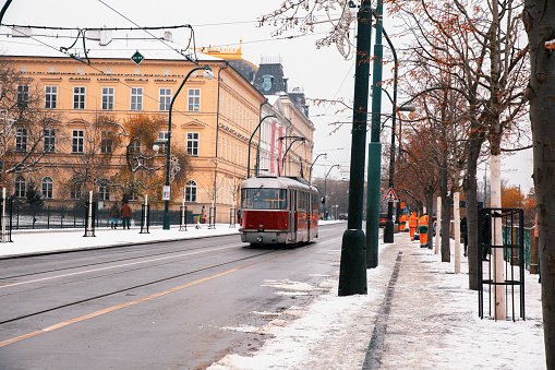 Quiete town street: tram passes by and cleaning workers remove snow