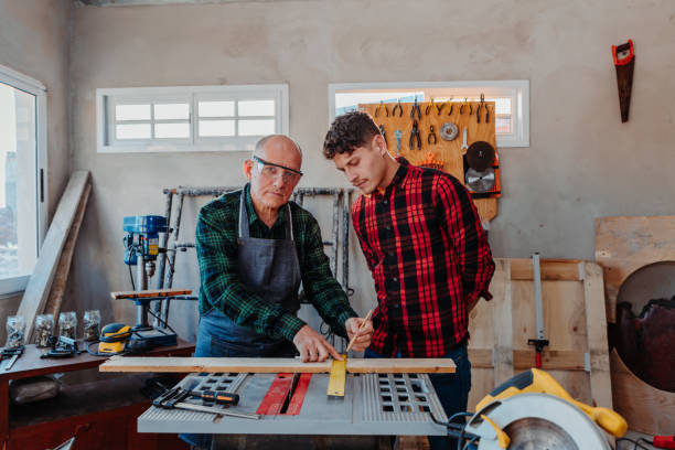 istock Senior carpenter teaching a younger man how to work 1454780824