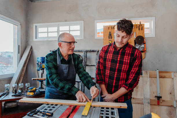 istock Senior carpenter teaching a younger man how to work 1454780830