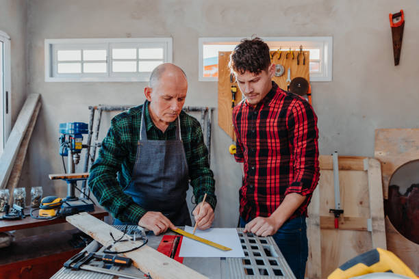 istock Senior carpenter teaching a younger man how to work 1454780837