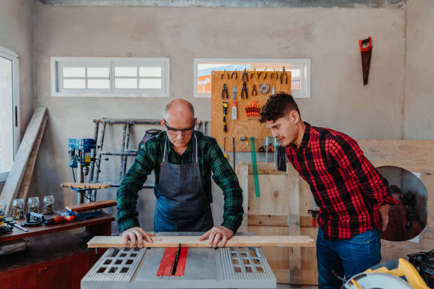 istock Senior carpenter teaching a younger man how to work 1454780857