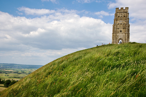 Panoramic view of the solitary medieval tower perched on the grassy summit of the terraced hill overlooking Glastonbury, famous for its new age truth seekers, ley lines and small pop concert. Adobe RGB 1998 color profile.