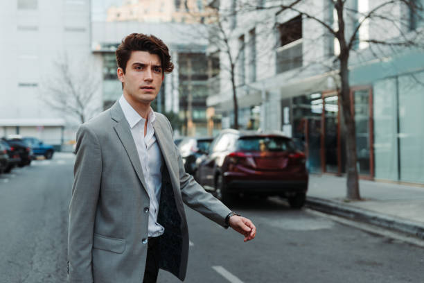 A serious young Caucasian guy dressed professionally walking on a stree