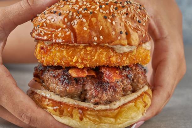 istock Mans hand holding a meat burger 1454783194