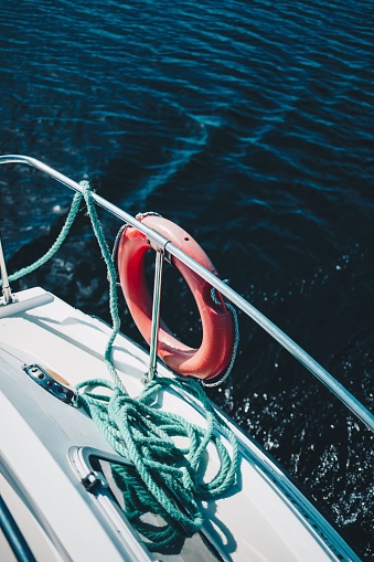 A vertical shot of a lifesaving ring and rope on the side of a boat