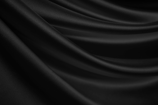 Abstract black background. Silk satin fabric. Curtain. Drapery. Luxury background for design. Beautiful soft folds.