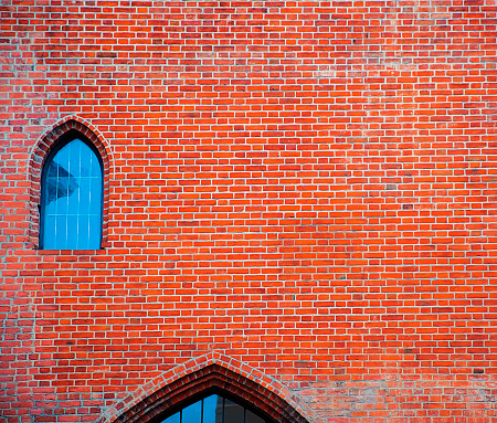 Red bricked wall with the small arched window