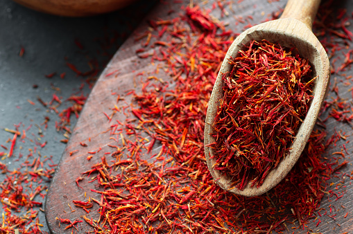 Heap of dried saffron spice in spoon on rustic background, spices and herbs concept (Crocus sativus)