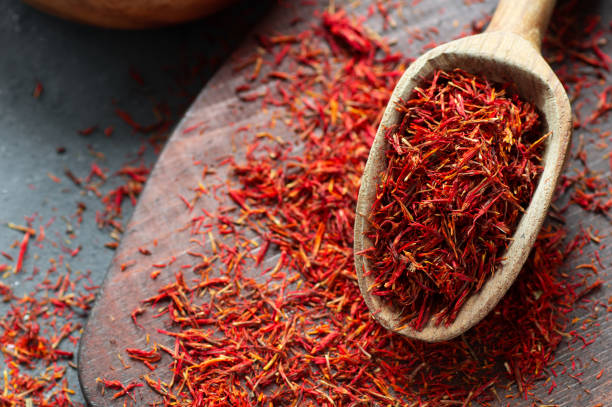 Heap of dried saffron spice in spoon on rustic background, spices and herbs concept (Crocus sativus) stock photo