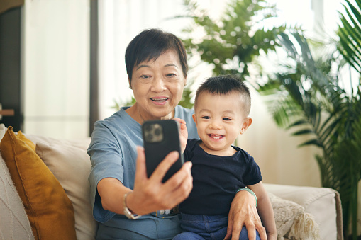 A little boy in Hong Kong and his grand mother looking happy as they use a smartphone