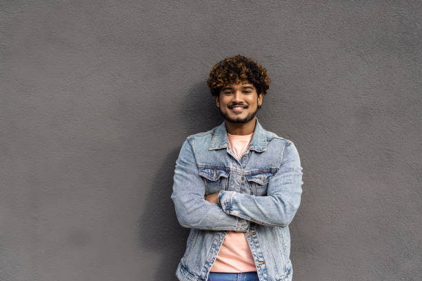 istock Handsome man with beard and crossed arms looking at camera. Middle eastern man isolated against grey wall and smiling. Satisfied indian guy looking at camera with a big laugh. 1454792178