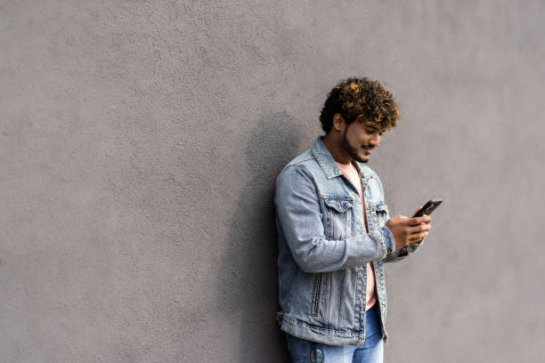 istock Portrait of indian man having phone in hands, checking email, using 3G, wi-fi internetvisolated on grey background 1454792309