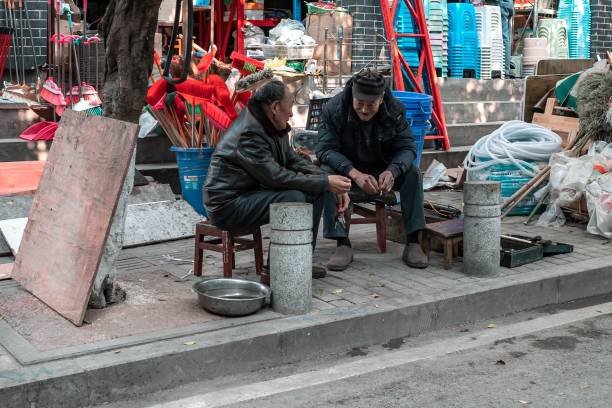 close up de dois homens chineses sentados na rua e conversando - street stall - fotografias e filmes do acervo