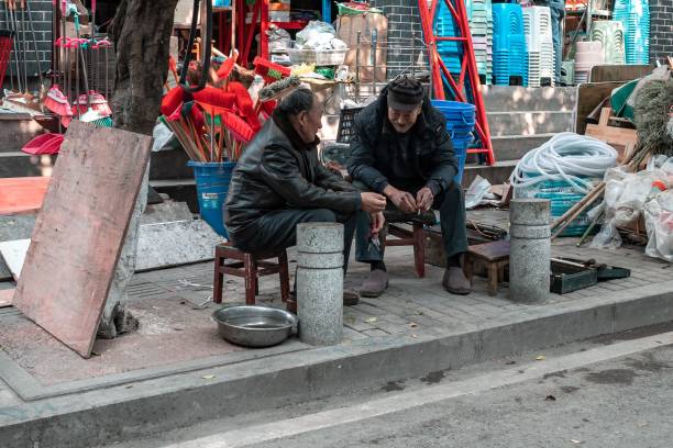 крупный план двух китайцев, сидящих на улице и болтающих - street stall стоковые фото и изображения