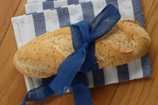 Whole Grain bread with flax seeds with blue tied bow on a wooden table