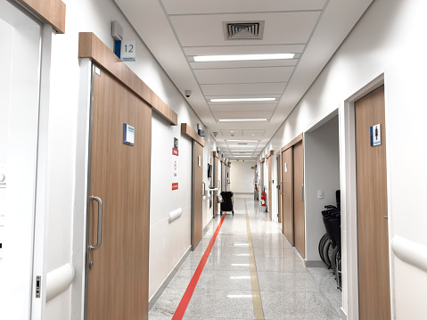 a long hospital corridor with green walls and white doors and lamps on the ceiling. interior of a medical institution.