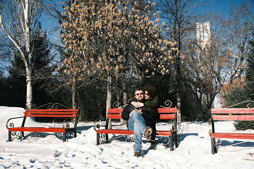 Mature couple is sitting on winter park bench