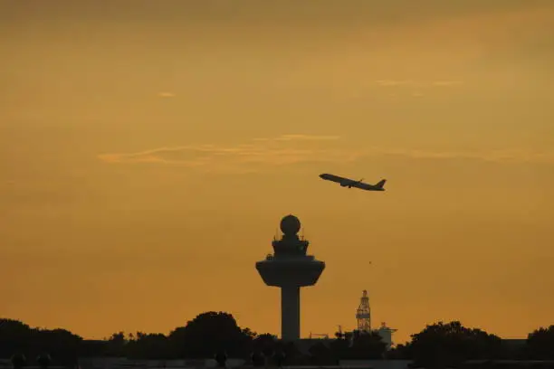Aircraft taking off over Changi Airport tower in dawn sky