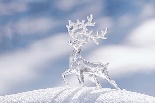 Christmas winter background - view of an ice deer on a snowdrift in a winter forest, sparkling in the rays of the winter sun with copy space for text