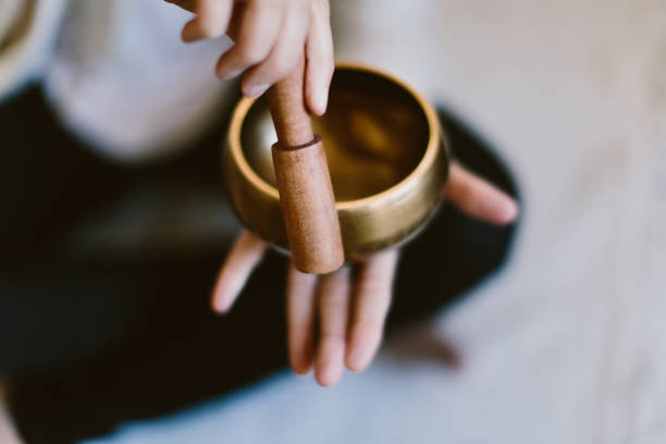 Angle shot of a woman using a Tibetan meditation singing bowl. An angle shot of a woman using a Tibetan meditation singing bowl. gong stock pictures, royalty-free photos & images