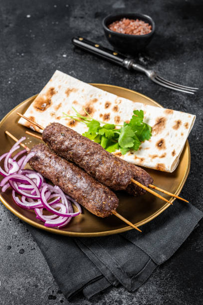 istock Lamb meat kofta kebab, onion and flat bread on plate. Black background. Top view 1454799545