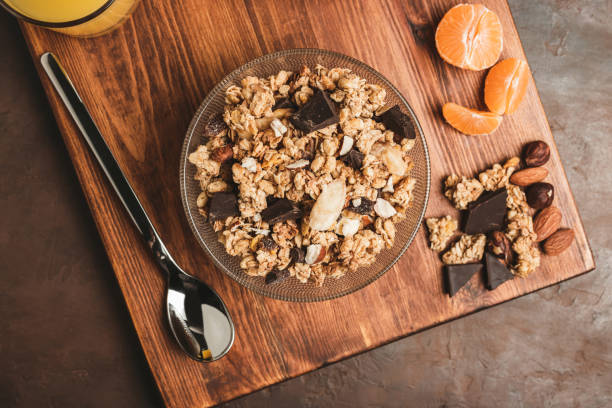 farine d’avoine aux céréales granola avec chocolat, fruist et noix dans un bol sur planche en bois foncé, vue de dessus - muesli photos et images de collection