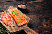Sliced Salted salmon fillet with herbs on a wooden board. Wooden background. Top view. Copy space