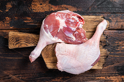 Uncooked Raw duck legs, Poultry meat on a wooden board. Wooden background. Top view.