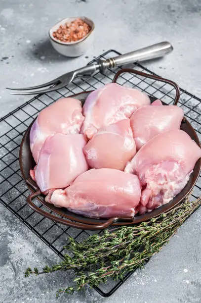 Photo of Boneless and skinless Raw Chicken leg thigh fillet. Gray background. Top view