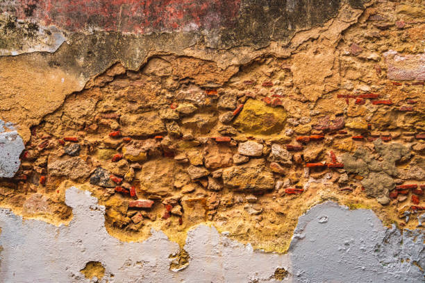 Fragment of an old brick wall with peeling cement plaster