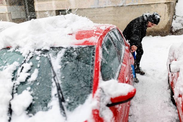istock Man is Cleaning a Snow from a Car with a Brush. 1454803075