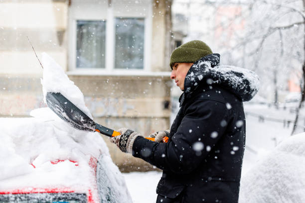 istock Man is Cleaning a Snow from a Car with a Snow Shovel. 1454803669