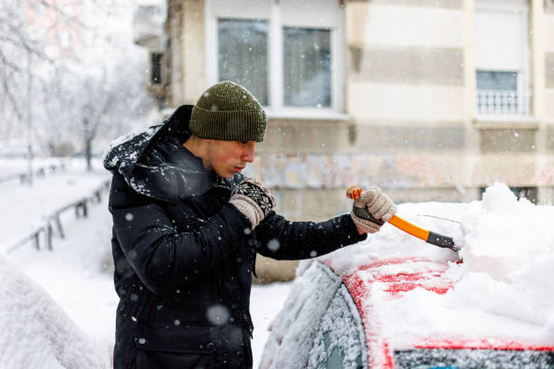 istock Man is Cleaning a Snow from a Car with a Snow Shovel. 1454803806