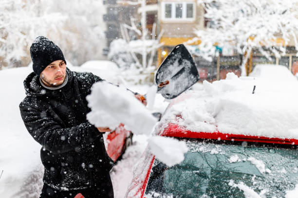 istock A Young Man is Cleaning Snow from a Car with a Shovel. 1454803852
