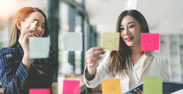 istock Two businesswoman meeting at office and use post it notes to share idea. Brainstorming concept. 1454804939